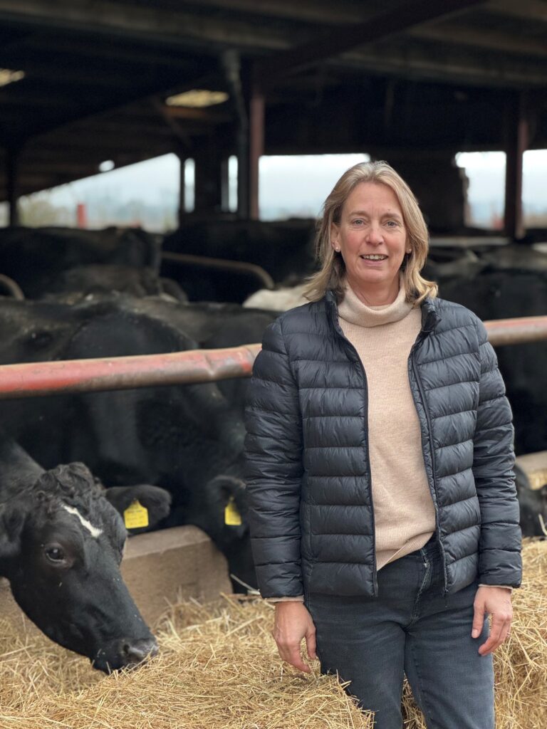 Emma Furnival stood in front of feeding cows in shed