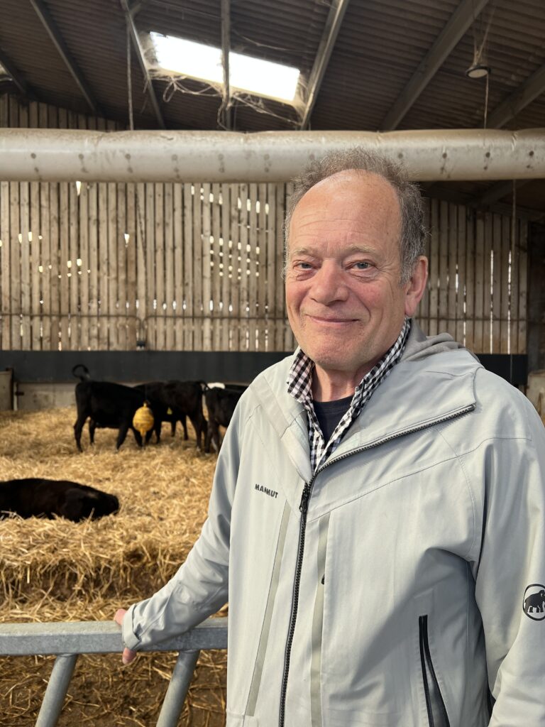 Jamie Robertson stood in cattle shed with cows in background