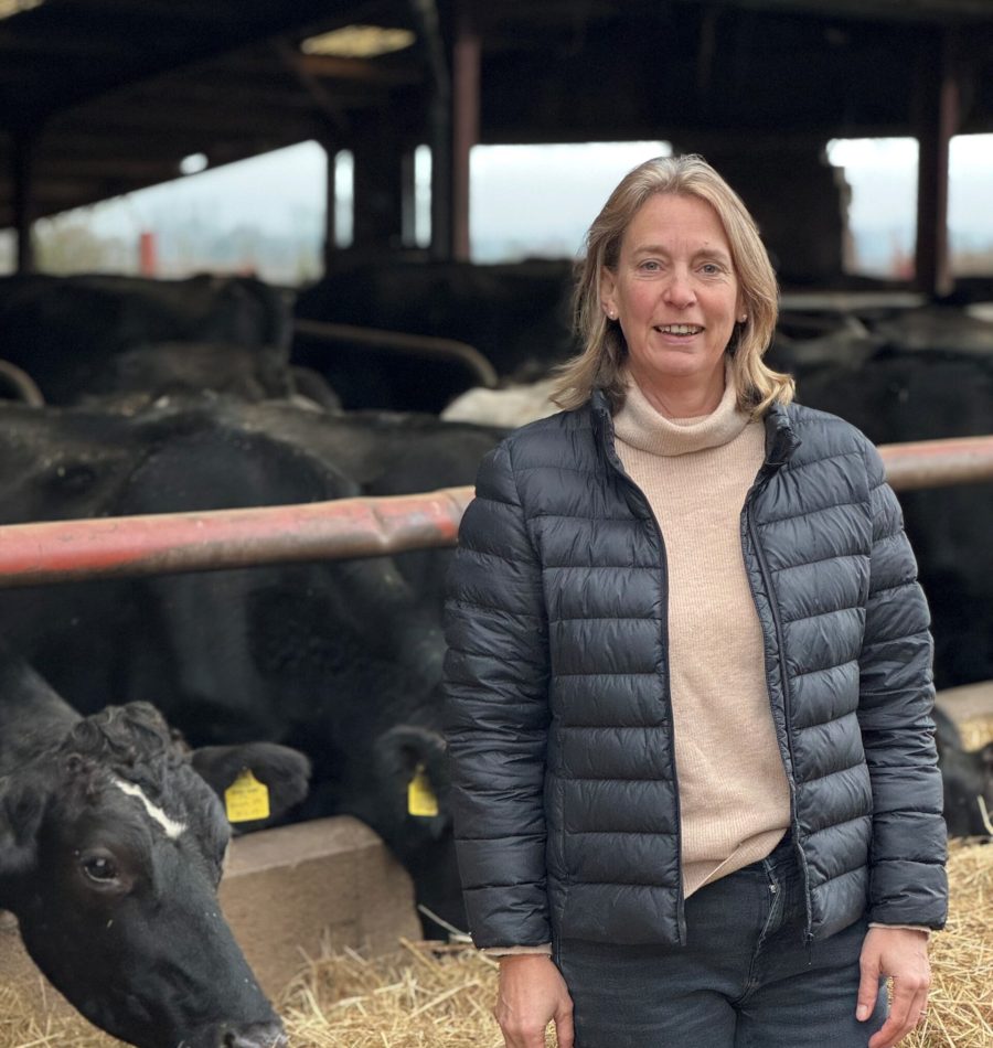 Emma Furnival stood in front of feeding cows in shed