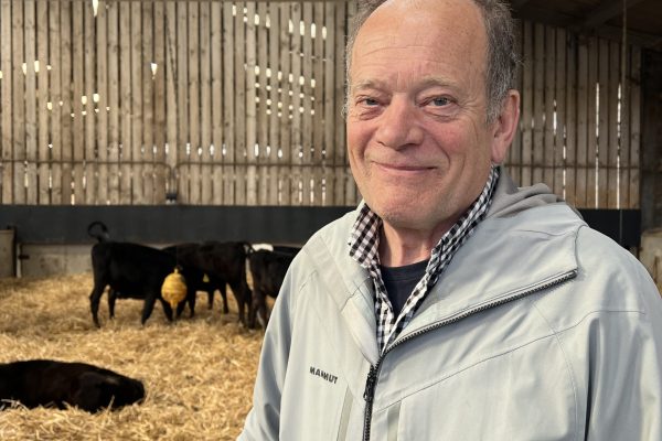 Jamie Robertson stood in cattle shed with cows in background